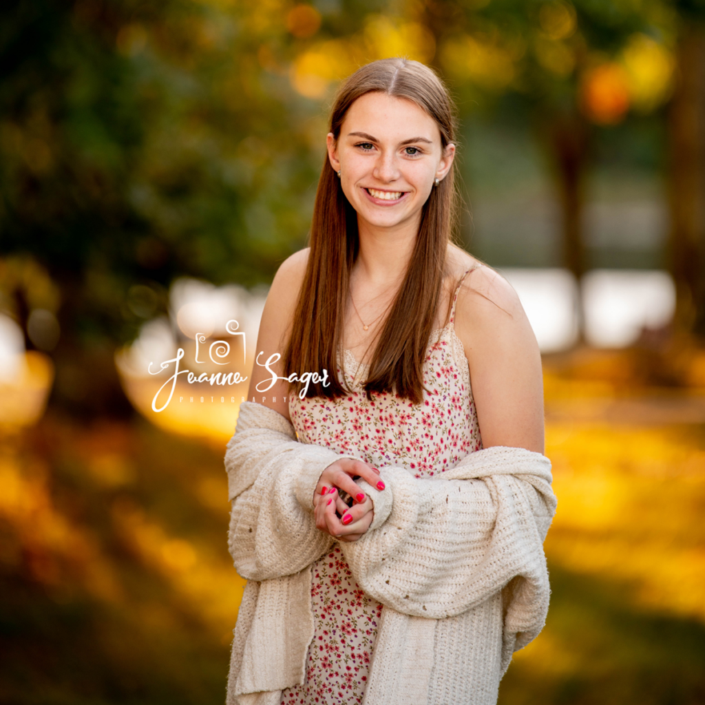 A teenage girl wearing a cardigan and dress at a fall family photo session