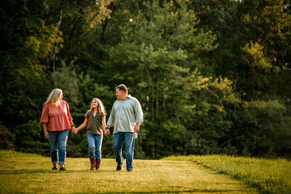a family of 3 walks in the golden sunlight of fall during a family photo session in callicoon ny
