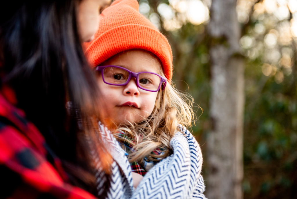 A mom snuggles with a little girl wrapped in a blanket during a family photo shoot in Bethel NY.