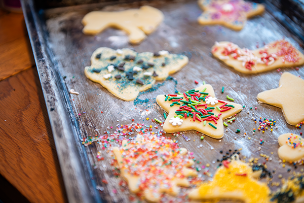 Raw cookies covered in sprinkles sit on an aged metal cookie sheet.